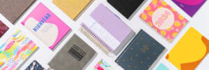 Colorful notebooks with different notebook covers arranged on white surface.